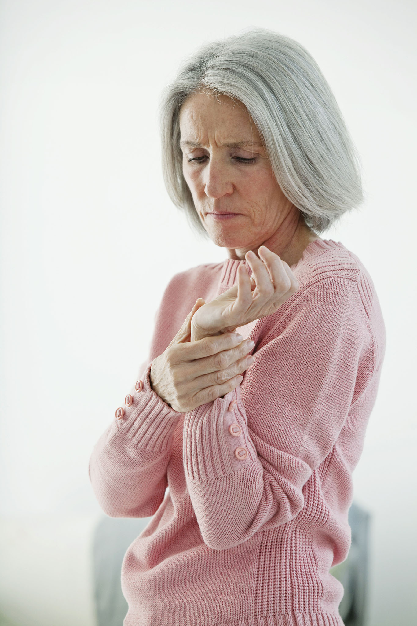 Elderly women examining her sore wrist