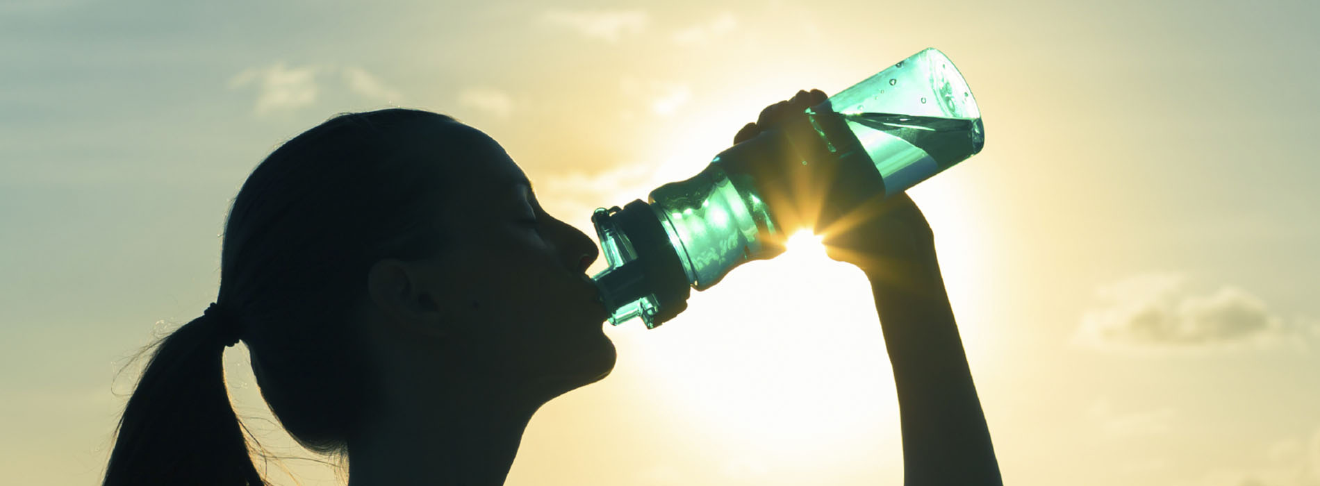 Silouette of a woman in profile drinking from a water bottle