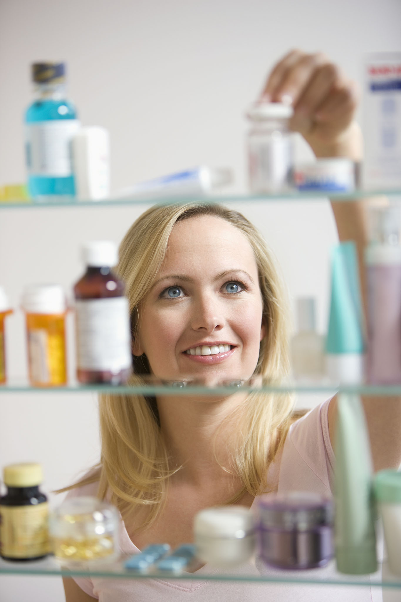 Smiling woman placing medicine on shelves