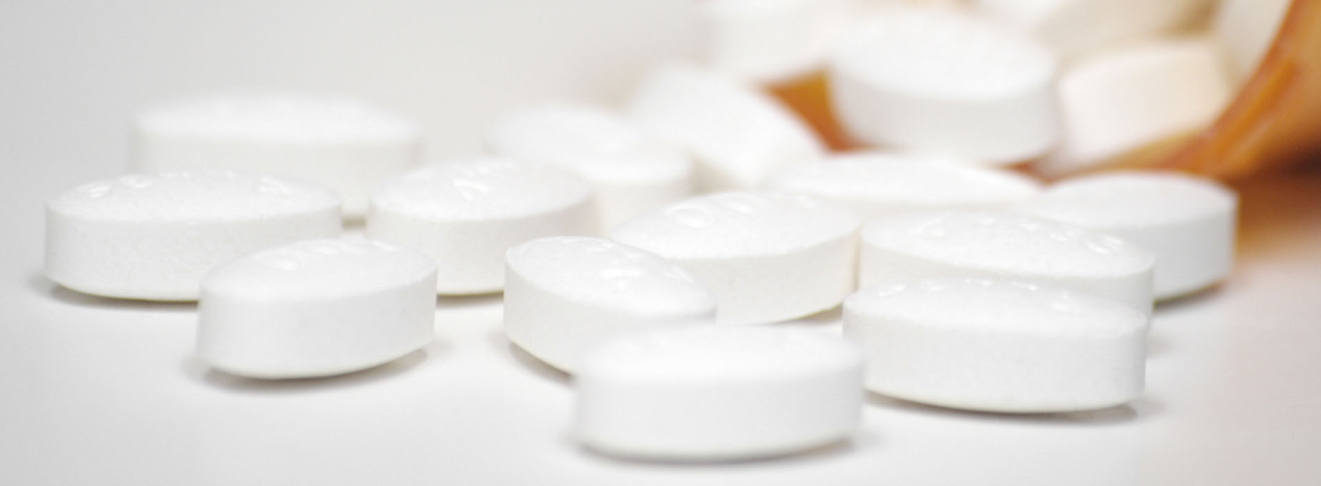 Close up of medicine bottle tipped over with pills spilling out