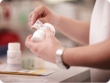 Close up of a pharmacist placing a customer's prescription label on a bottle