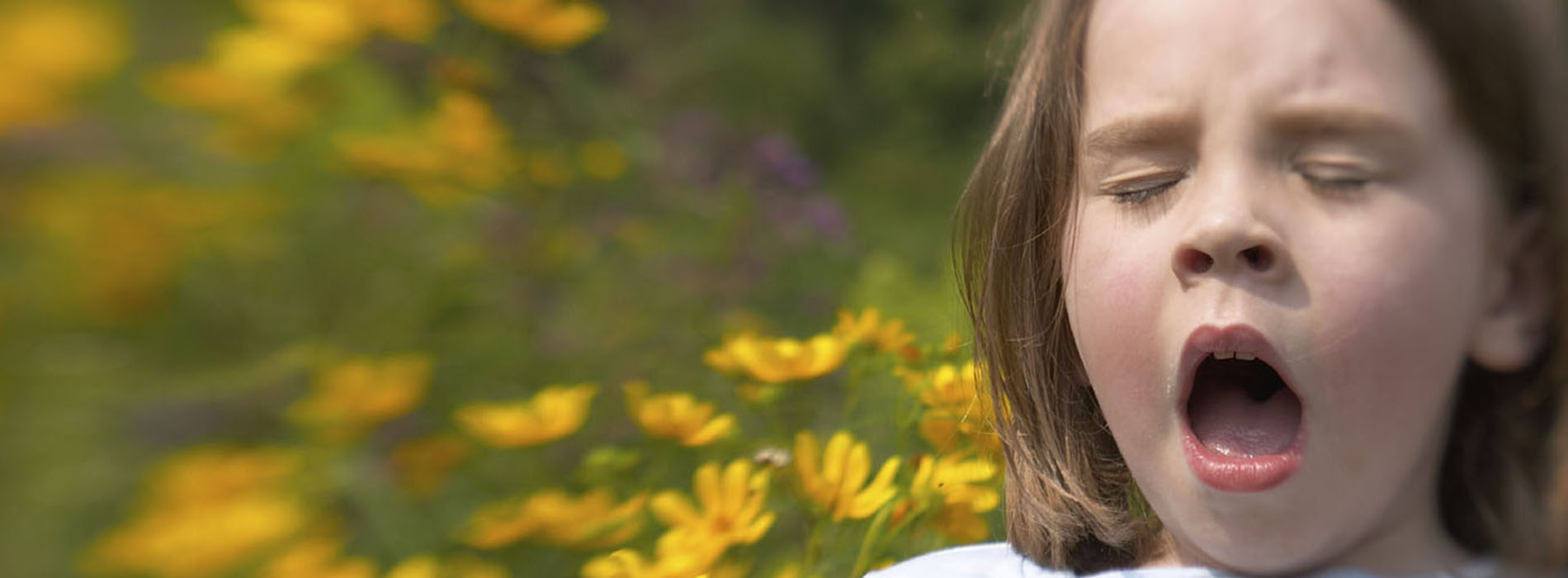 Girl sneezing and holding a bunch of yellow flowers