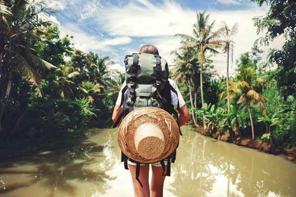 Back of a backpacker in front of a tropical paradise