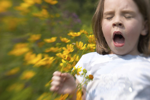 Girl sneezing and holding a bunch of yellow flowers 
