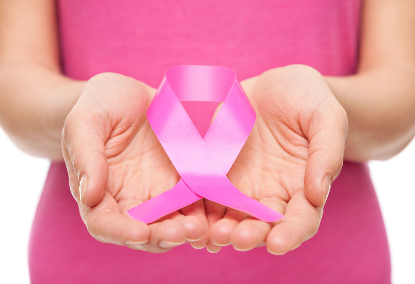 Close up of woman in a pink T-shirt, in her hands she is holding a pink ribbon