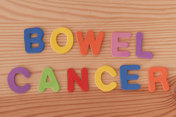 Colour letters spelling out Bowel Cancer against wooden backrgound
