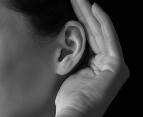 Close up of woman cupping her hand behind her ear