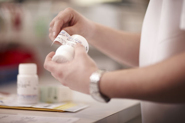 Pharmacist placing a label on a prescription bottle